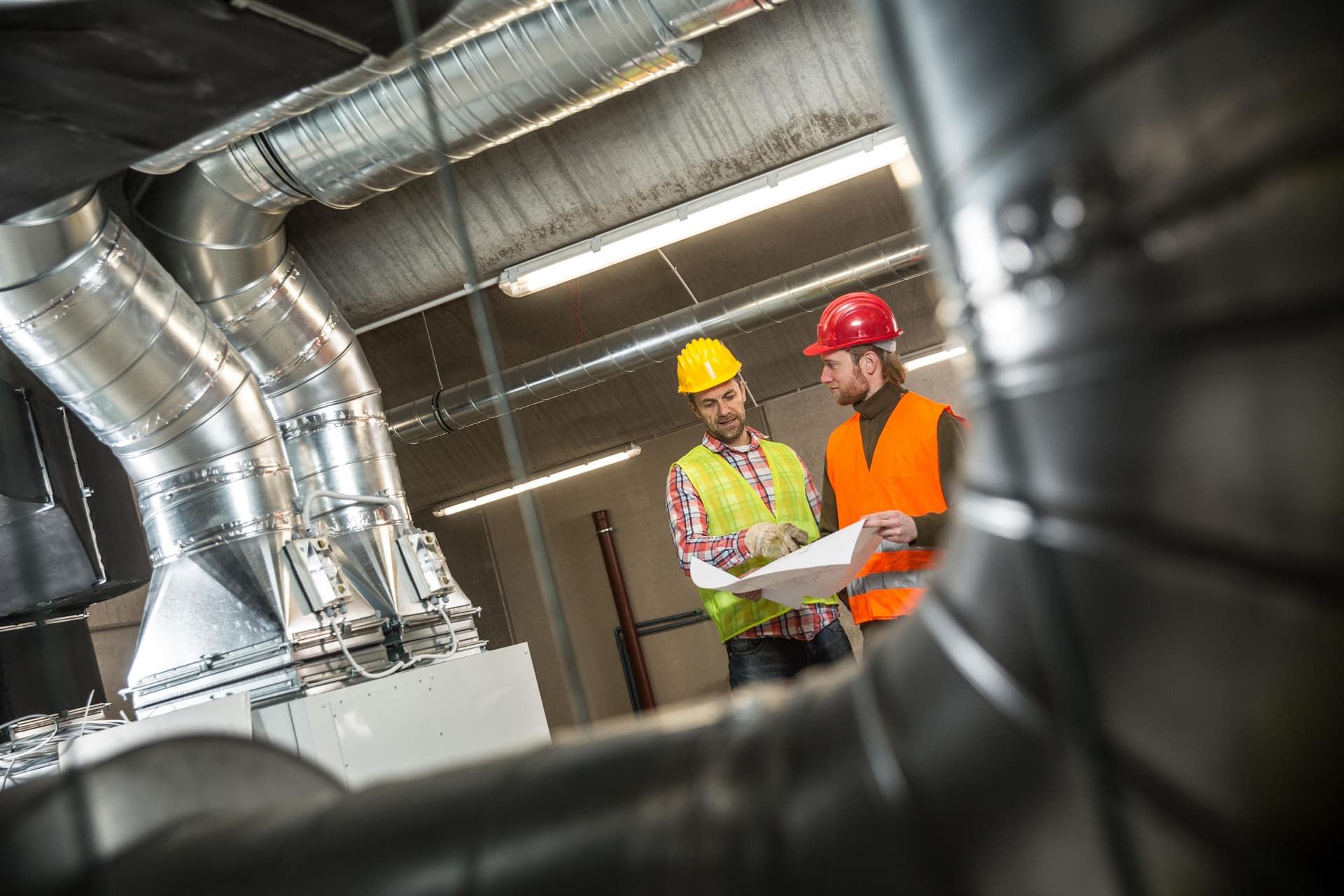 Mechanical engineers reviewing HVAC ductwork plans on a job site