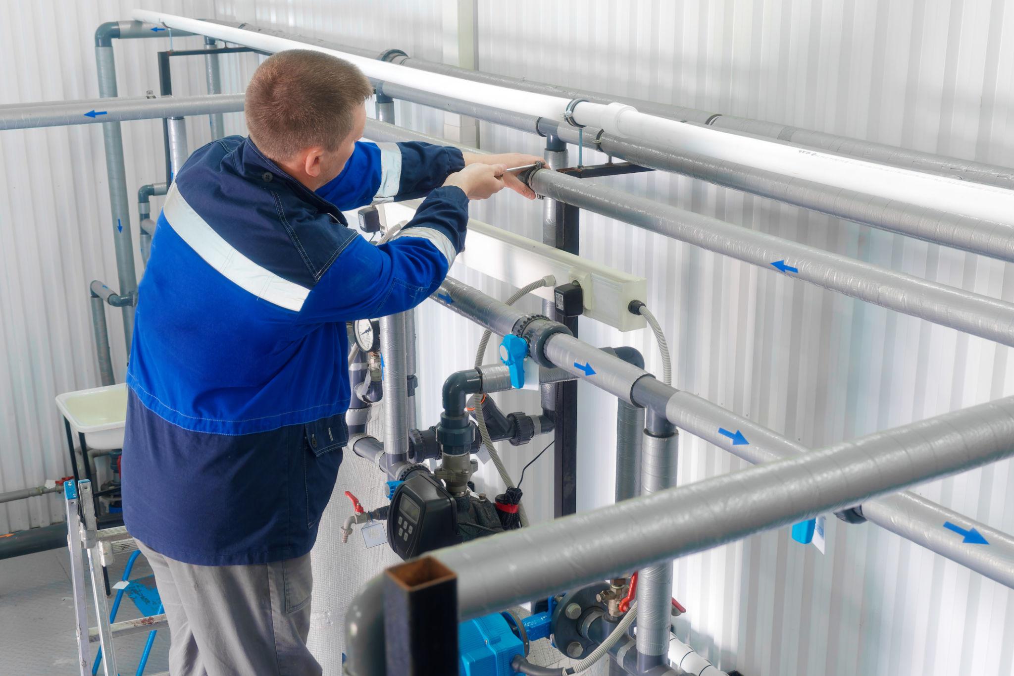 Plumber servicing commercial kitchen piping and equipment