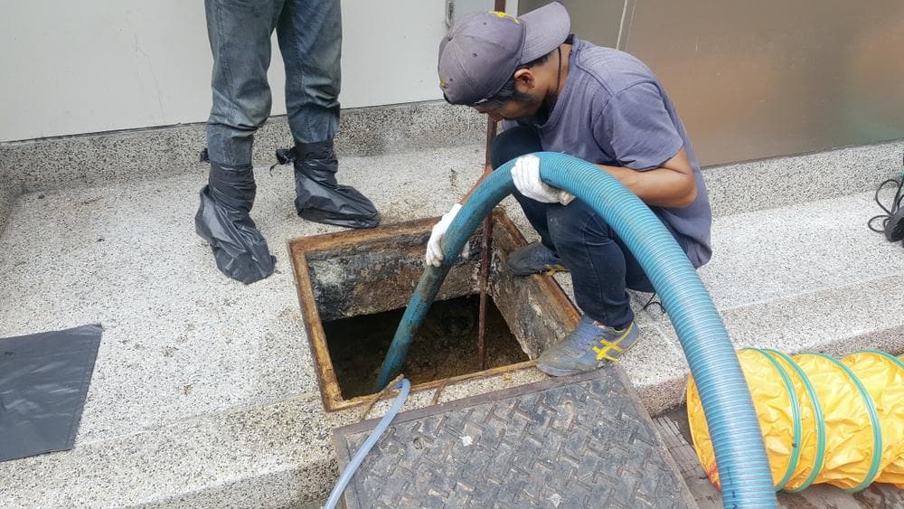 Technicians cleaning a commercial grease trap