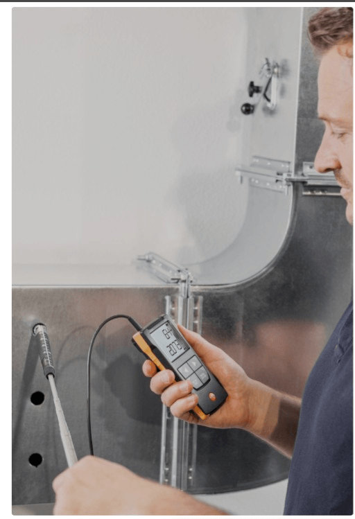 HVAC technician measuring airflow in commercial ductwork during air balancing