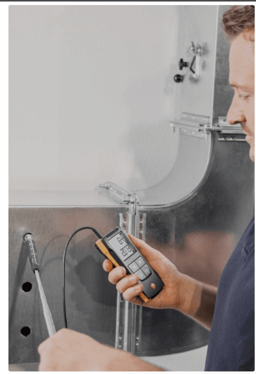 HVAC technician measuring airflow in commercial ductwork during air balancing