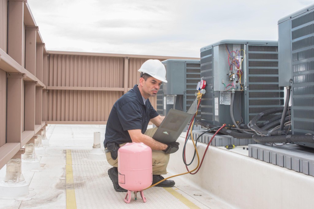 Commercial HVAC technician servicing rooftop units on a restaurant building