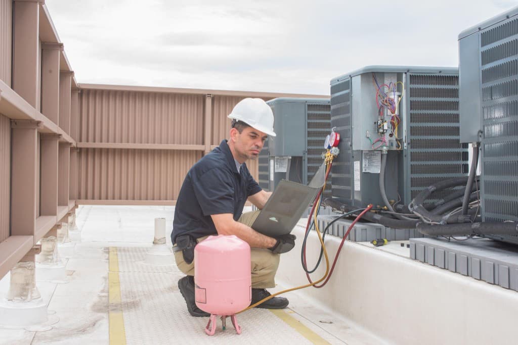 Commercial HVAC technician servicing rooftop units on a restaurant building