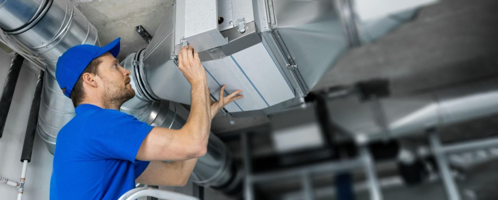 HVAC technician installing commercial ductwork in a restaurant facility ceiling
