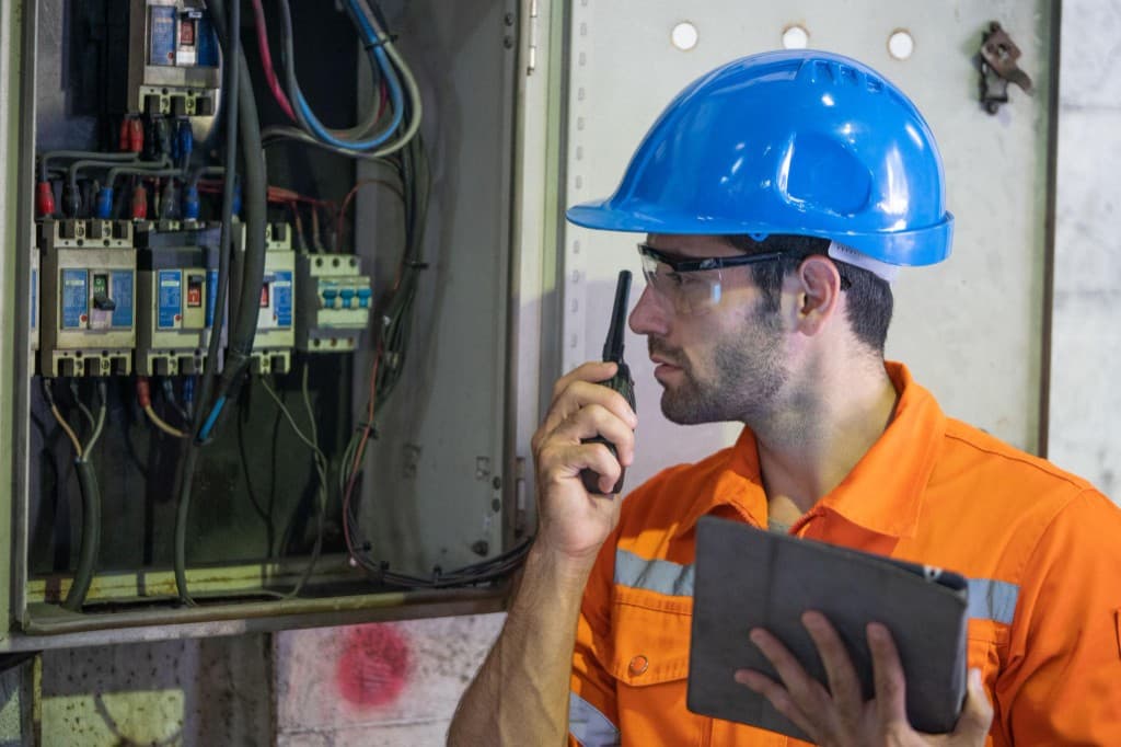 Two licensed electricians reviewing a commercial electrical control panel