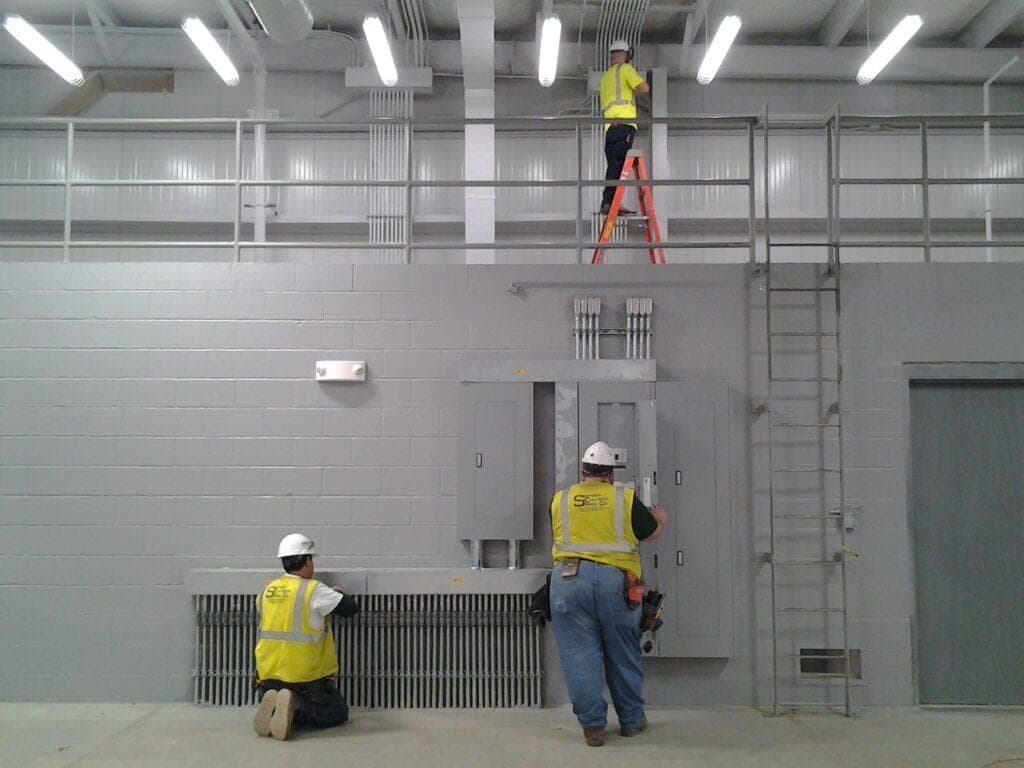 Commercial electricians performing emergency electrical repair in an industrial facility