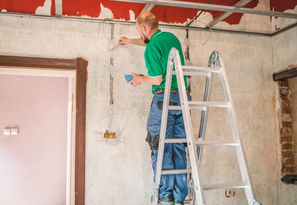 Electrician on a ladder running wiring during a commercial tenant improvement project