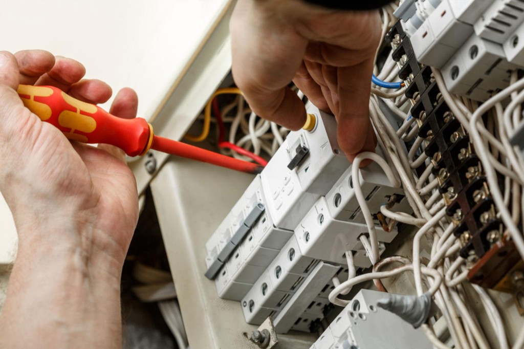 Electrician servicing a commercial circuit breaker panel with insulated tools