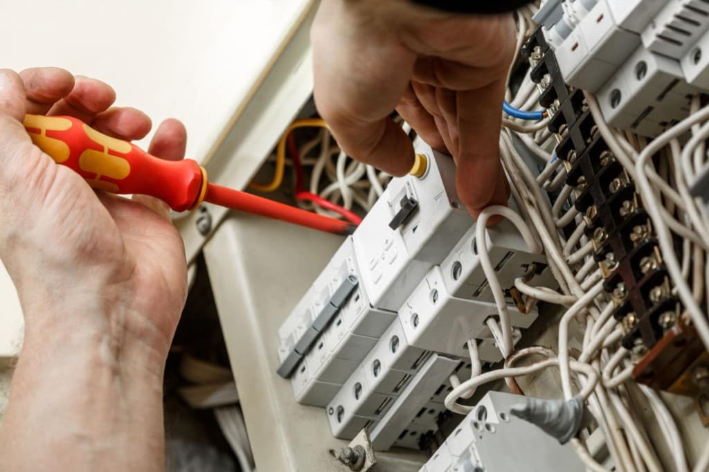 Electrician servicing a commercial circuit breaker panel with insulated tools