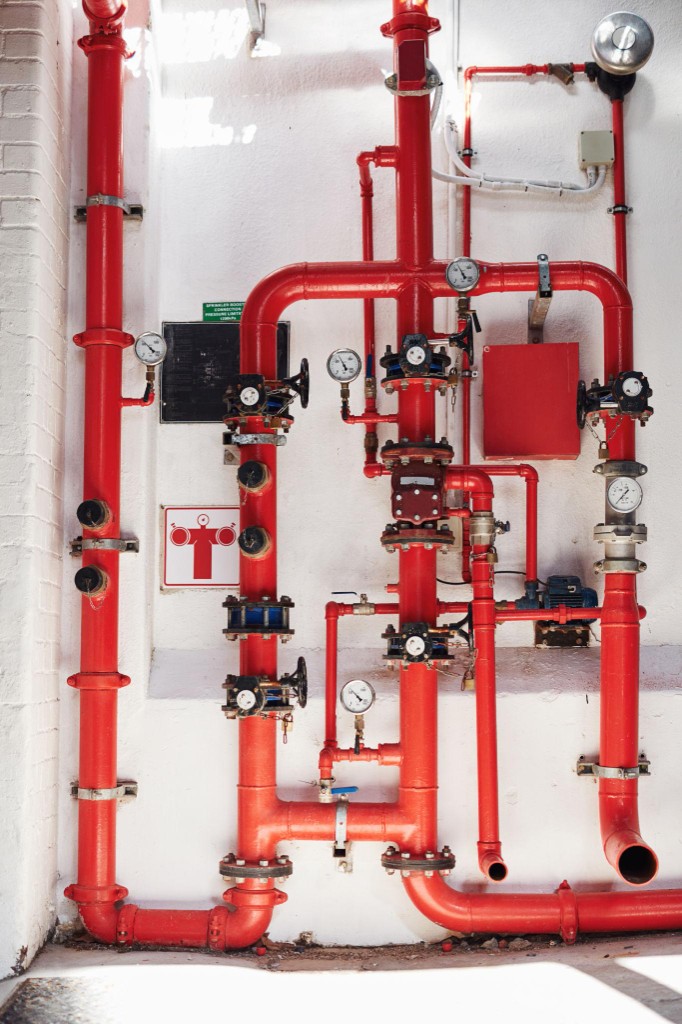 Red fire suppression piping and valves mounted on a commercial facility wall
