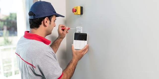 Technician repairing a commercial fire suppression control panel and keypad