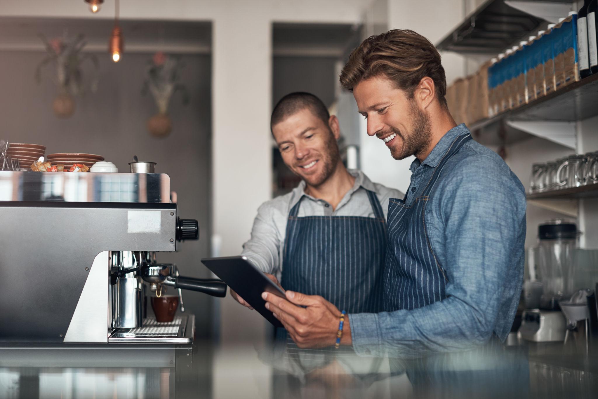 Restaurant owners reviewing information on a tablet in a commercial kitchen