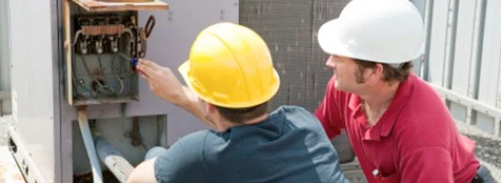 Two workers inspecting electrical panel